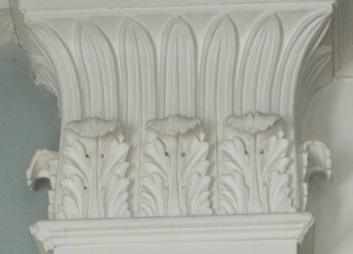 Ornamentation in the double parlors includes carved pilasters with Corinthian capitals and double anthemia.